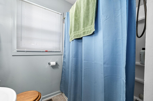 bathroom with a shower with curtain and toilet