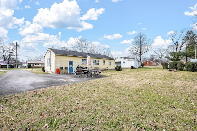 back of house with a patio area and a lawn
