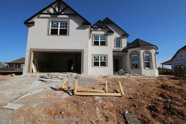 rear view of property featuring a garage, brick siding, and dirt driveway