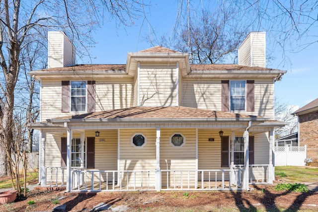 view of front of house with covered porch, fence, and a chimney