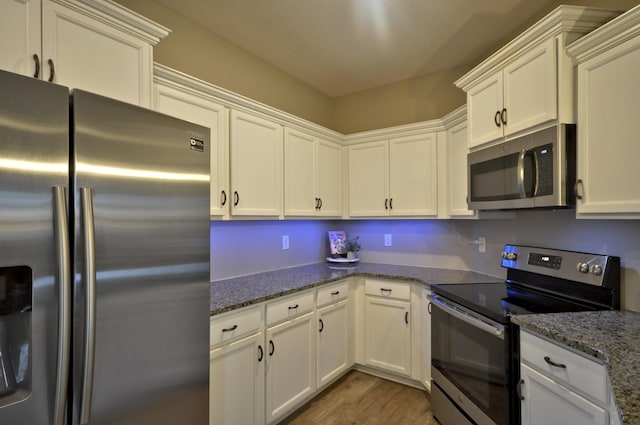 kitchen with appliances with stainless steel finishes, white cabinets, dark wood-type flooring, and dark stone counters