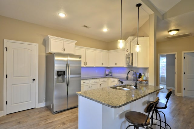 kitchen with white cabinetry, dark stone countertops, decorative light fixtures, sink, and appliances with stainless steel finishes