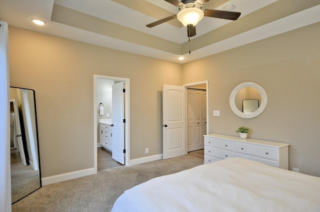 carpeted bedroom with ensuite bath and a raised ceiling