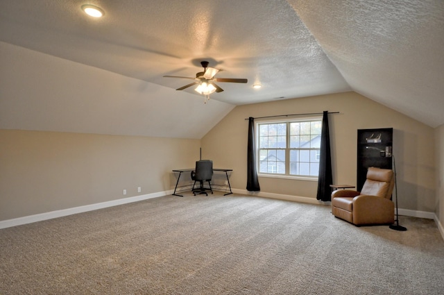 unfurnished office featuring lofted ceiling, ceiling fan, carpet floors, and a textured ceiling