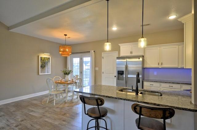 kitchen featuring white cabinets, sink, dark stone counters, and stainless steel refrigerator with ice dispenser