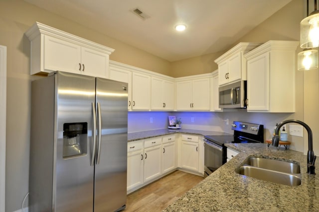 kitchen with white cabinetry, hanging light fixtures, sink, light stone counters, and appliances with stainless steel finishes