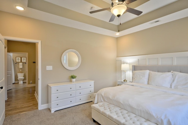 carpeted bedroom featuring a tray ceiling and ceiling fan