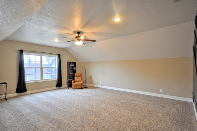 additional living space featuring lofted ceiling, ceiling fan, carpet flooring, and a textured ceiling