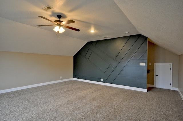 additional living space featuring ceiling fan, carpet flooring, vaulted ceiling, and a textured ceiling