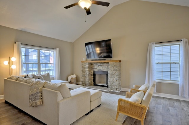 living room featuring high vaulted ceiling, hardwood / wood-style flooring, ceiling fan, and a fireplace