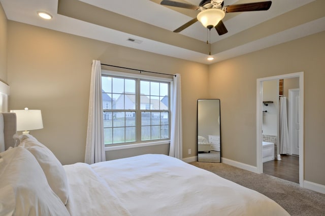 carpeted bedroom featuring a raised ceiling and ceiling fan