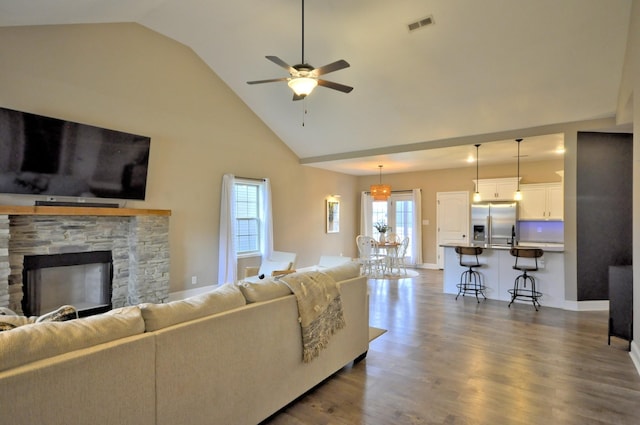 living room featuring hardwood / wood-style floors, high vaulted ceiling, ceiling fan, and a fireplace