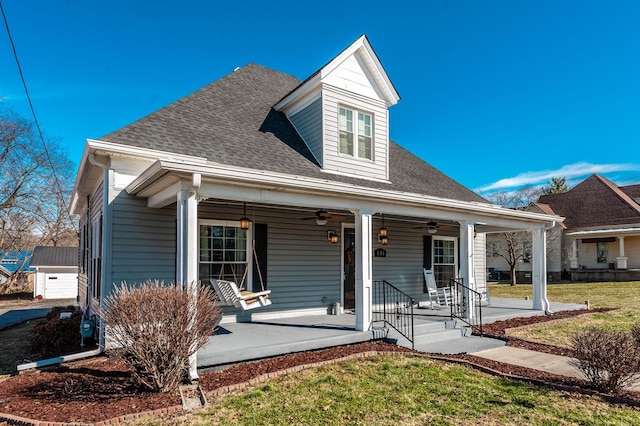 view of front facade with covered porch, a shingled roof, a ceiling fan, and a front yard