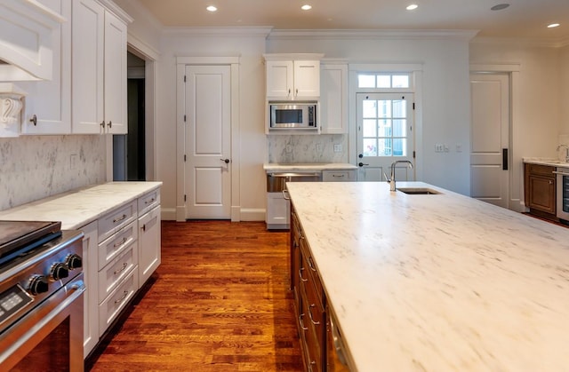 kitchen featuring sink, stainless steel microwave, white cabinetry, dark wood-type flooring, and light stone countertops