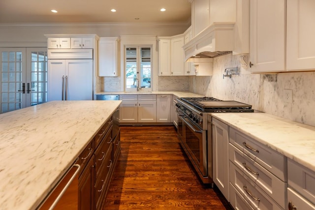 kitchen featuring high end appliances, white cabinetry, and light stone countertops