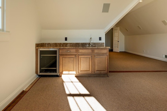 interior space featuring dark colored carpet, lofted ceiling, sink, and beverage cooler