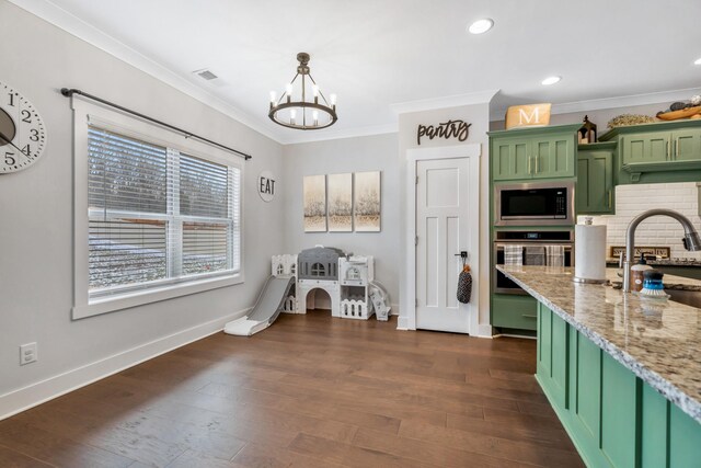 kitchen with light stone counters, appliances with stainless steel finishes, dark wood-type flooring, pendant lighting, and green cabinetry