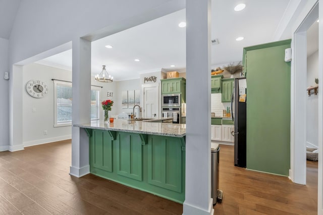 kitchen featuring light stone counters, dark wood-style flooring, stainless steel appliances, green cabinets, and a sink