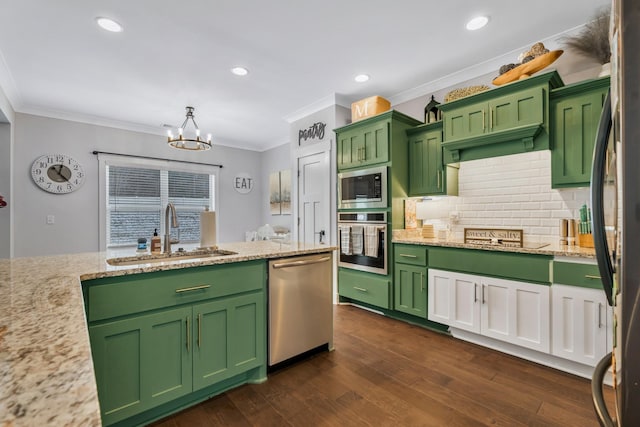 kitchen with green cabinetry, stainless steel appliances, a sink, and decorative light fixtures