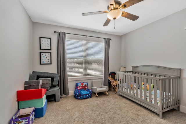 bedroom featuring carpet floors, a nursery area, and a ceiling fan