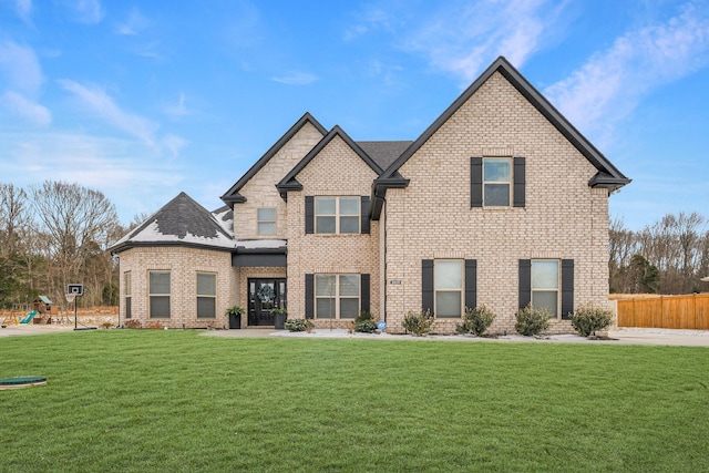 view of front facade featuring a front yard, brick siding, and fence