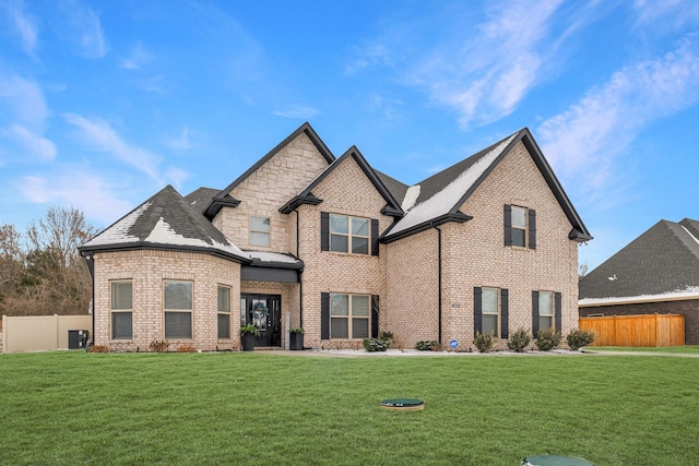 view of front of property with brick siding, fence, a front lawn, and central air condition unit