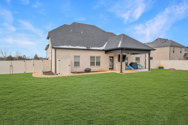 rear view of property featuring a fenced backyard, roof with shingles, a lawn, a gate, and a patio area