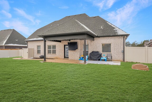 rear view of house featuring a shingled roof, a lawn, a patio area, and a fenced backyard