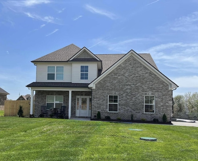 view of front of home featuring a front lawn, a shingled roof, fence, and brick siding