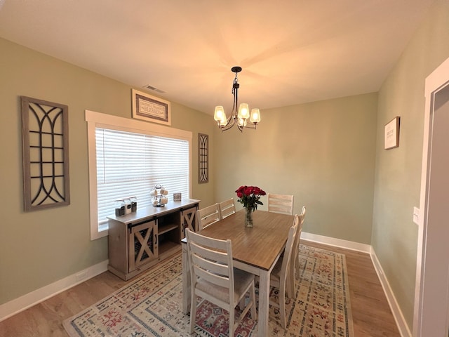 dining room with visible vents, baseboards, a chandelier, and wood finished floors