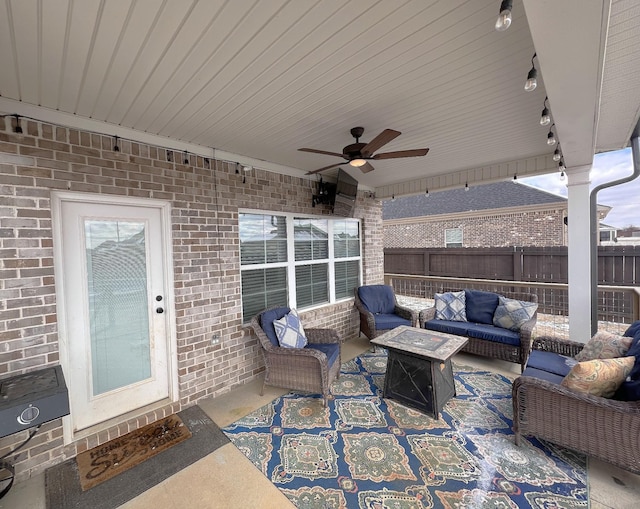 view of patio featuring ceiling fan, an outdoor living space with a fire pit, and fence