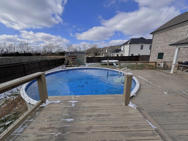 view of pool with a fenced in pool, a fenced backyard, a playground, and a deck