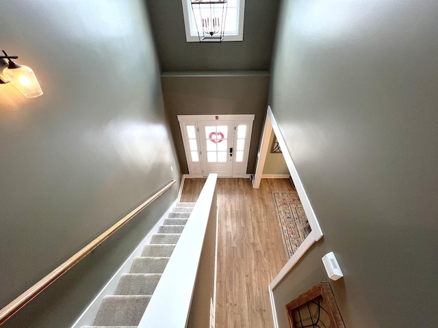 interior space featuring light wood-type flooring, a towering ceiling, baseboards, and stairs