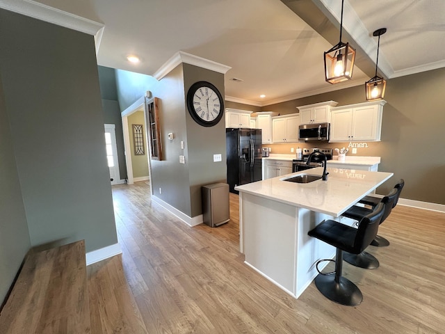 kitchen with a breakfast bar area, stainless steel appliances, hanging light fixtures, white cabinets, and a sink