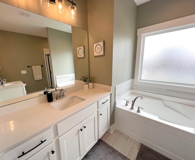 full bath with visible vents, a garden tub, and vanity