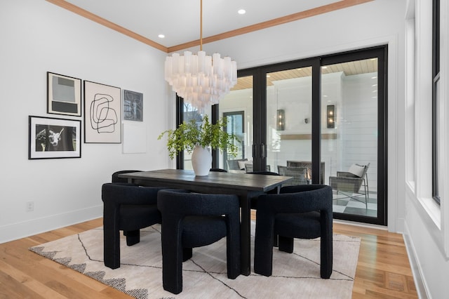 dining area featuring light wood-type flooring, crown molding, and a notable chandelier