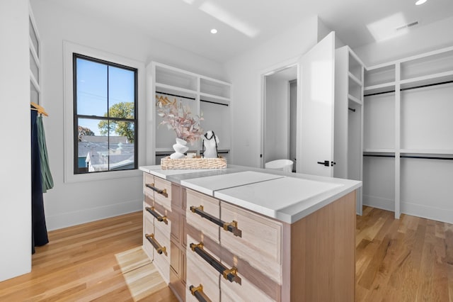 walk in closet with light hardwood / wood-style floors