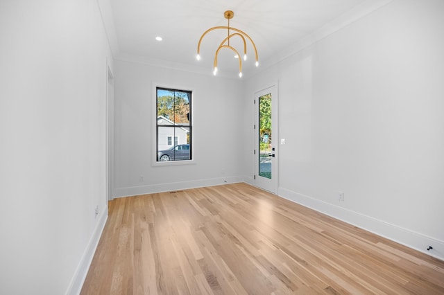 unfurnished room with ornamental molding, light hardwood / wood-style floors, and an inviting chandelier