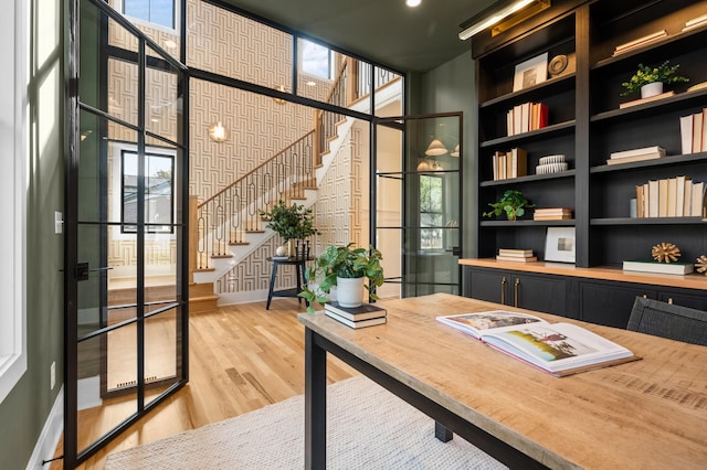 home office with a high ceiling, a wall of windows, and hardwood / wood-style floors