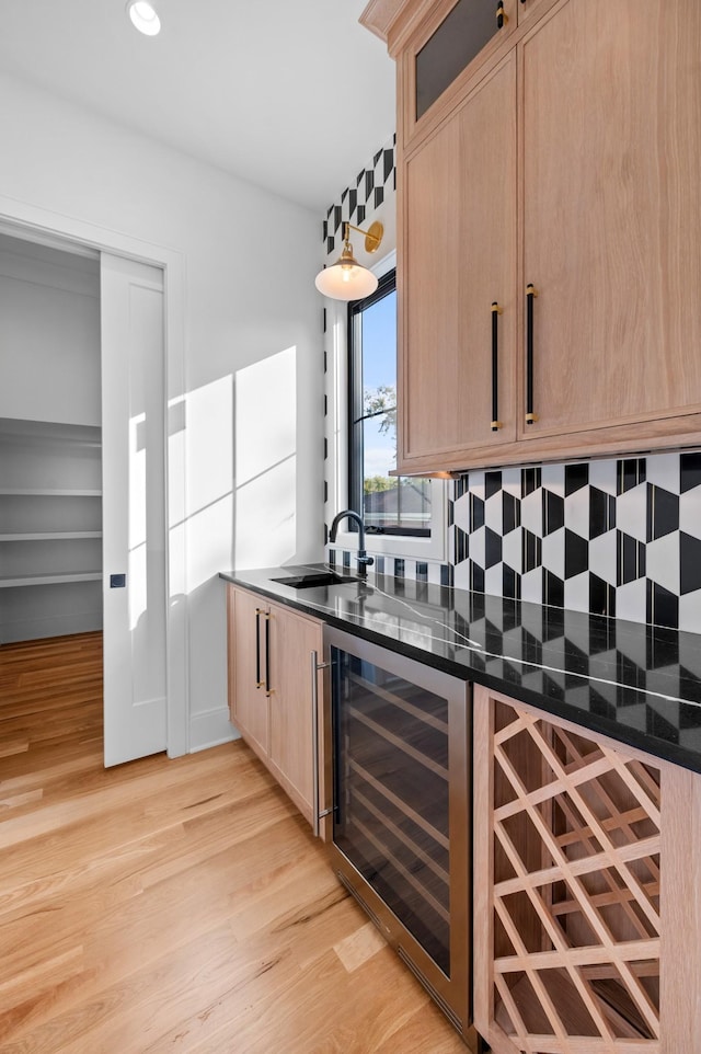 bar featuring sink, dark stone countertops, light brown cabinets, and wine cooler