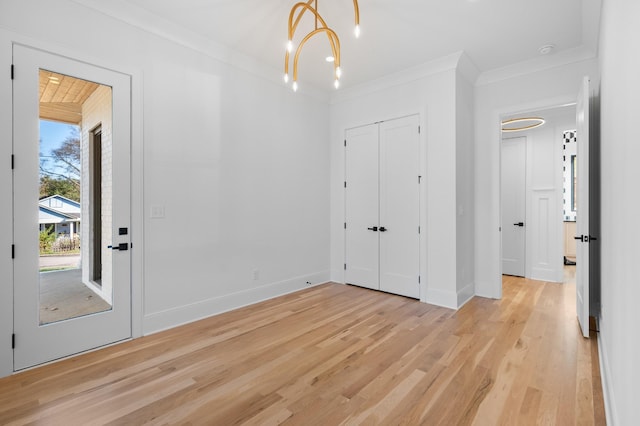 interior space with light hardwood / wood-style floors, a chandelier, crown molding, and a closet