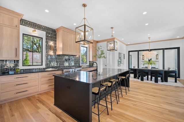 kitchen featuring light hardwood / wood-style floors, pendant lighting, backsplash, light brown cabinets, and a kitchen island