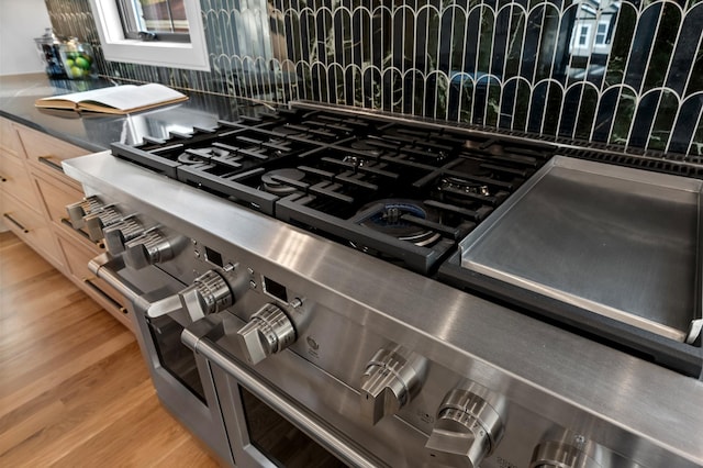 room details with range with two ovens, decorative backsplash, light brown cabinetry, and hardwood / wood-style floors