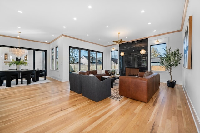 living room featuring light hardwood / wood-style floors, crown molding, and an inviting chandelier