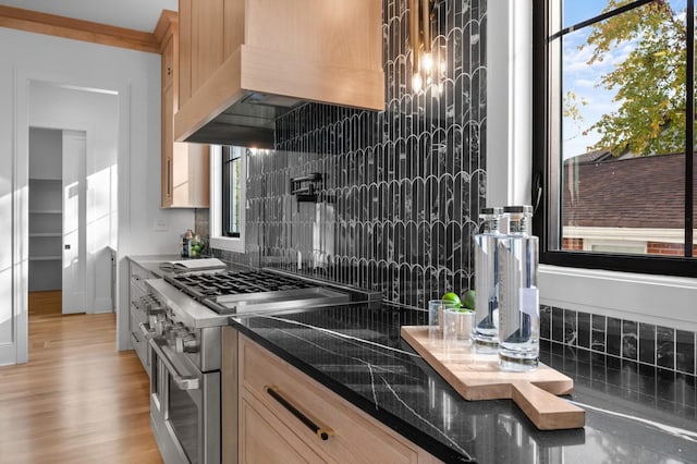 kitchen featuring custom exhaust hood, tasteful backsplash, range with two ovens, and light hardwood / wood-style flooring