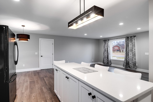 kitchen featuring a center island, black refrigerator, pendant lighting, and white cabinets