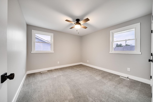 carpeted spare room with ceiling fan and plenty of natural light