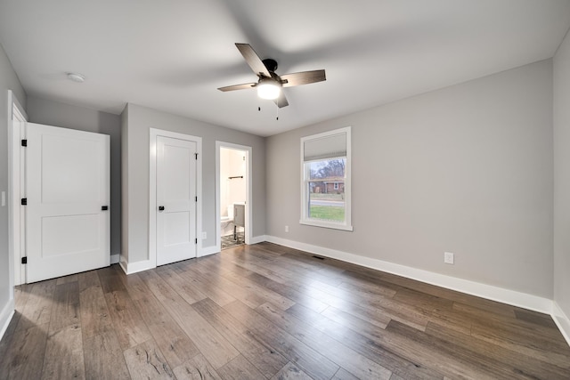 unfurnished bedroom with ensuite bathroom, ceiling fan, and wood-type flooring