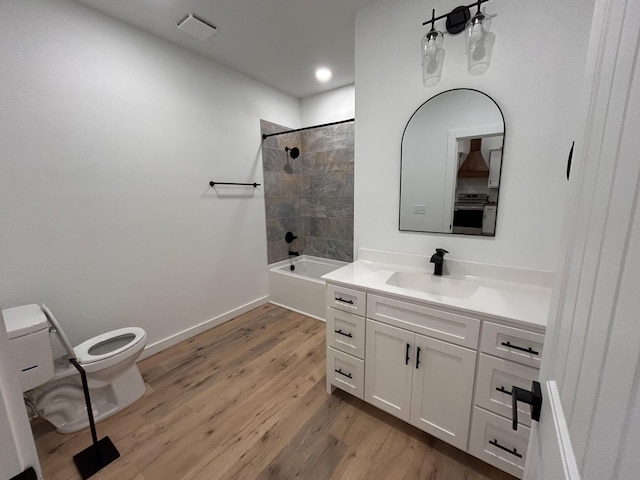 full bathroom featuring hardwood / wood-style flooring, vanity, tiled shower / bath, and toilet