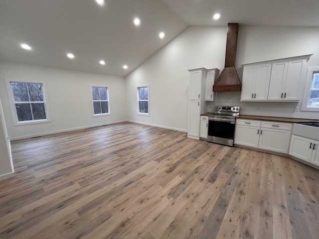 kitchen with light hardwood / wood-style flooring, white cabinetry, stainless steel electric range oven, and custom range hood